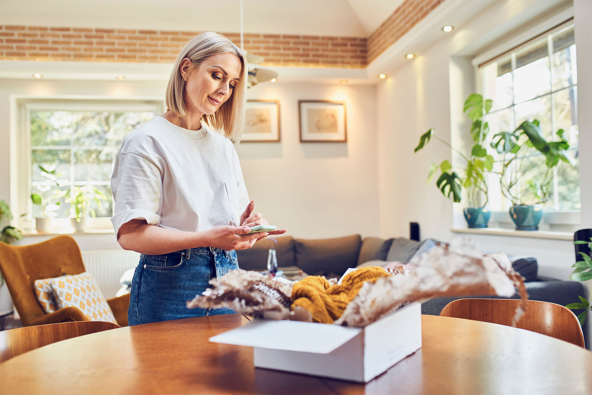 woman scrolling on cellphone while standing in the living room 